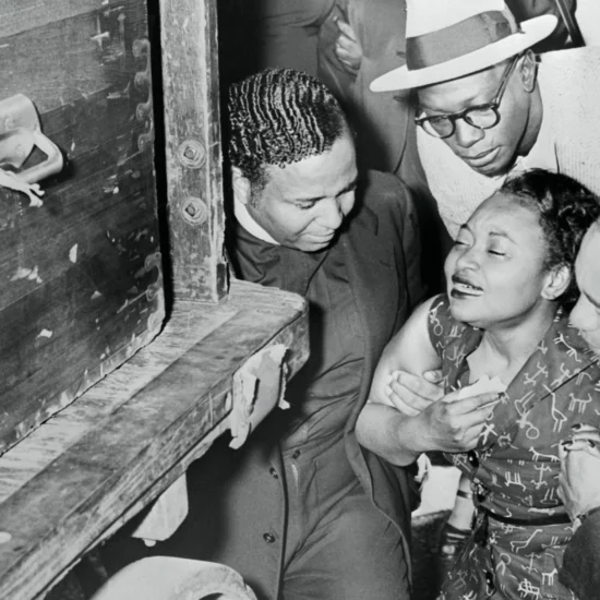 Mamie Till-Mobley being support by three men as she views her son's casket