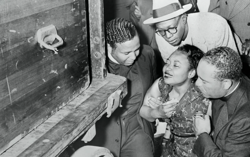 Mamie Till-Mobley being support by three men as she views her son's casket