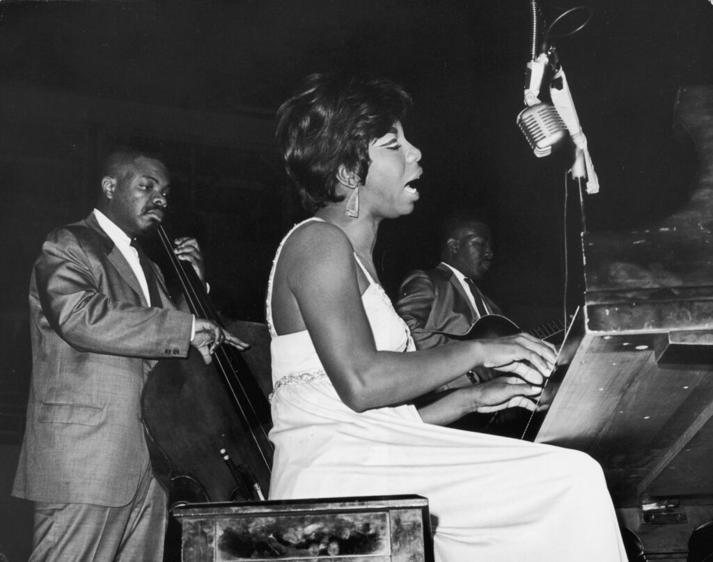 8th October 1964: American pianist and vocalist Nina Simone (1933 - 2003) sings while playing piano at the World's Fair, Singers' Bowl, Queens, New York.