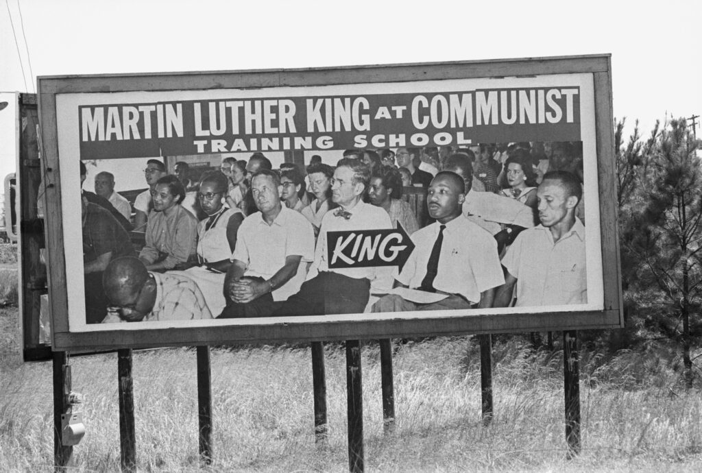 Billboards claiming to identify Dr Martin Luther King Jr at a communist training school stand on the route from Selma, Alabama to Montgomery taken by civil rights marchers, led by Dr King, protesting racial discrimination in voter rolls. The billboard in fact depicts Dr King at the Highlander Folk School at Mount Eagle in the 1940s.