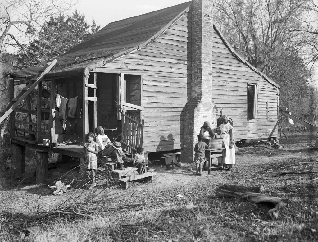 wo African American women wash clothes in the yard of a form slave shack on a Natchez, Mississippi plantation. 1938.
