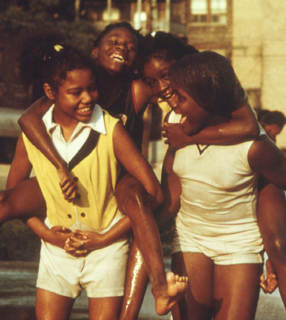 four young African American girls, two of them being carried on the other two girls' backs