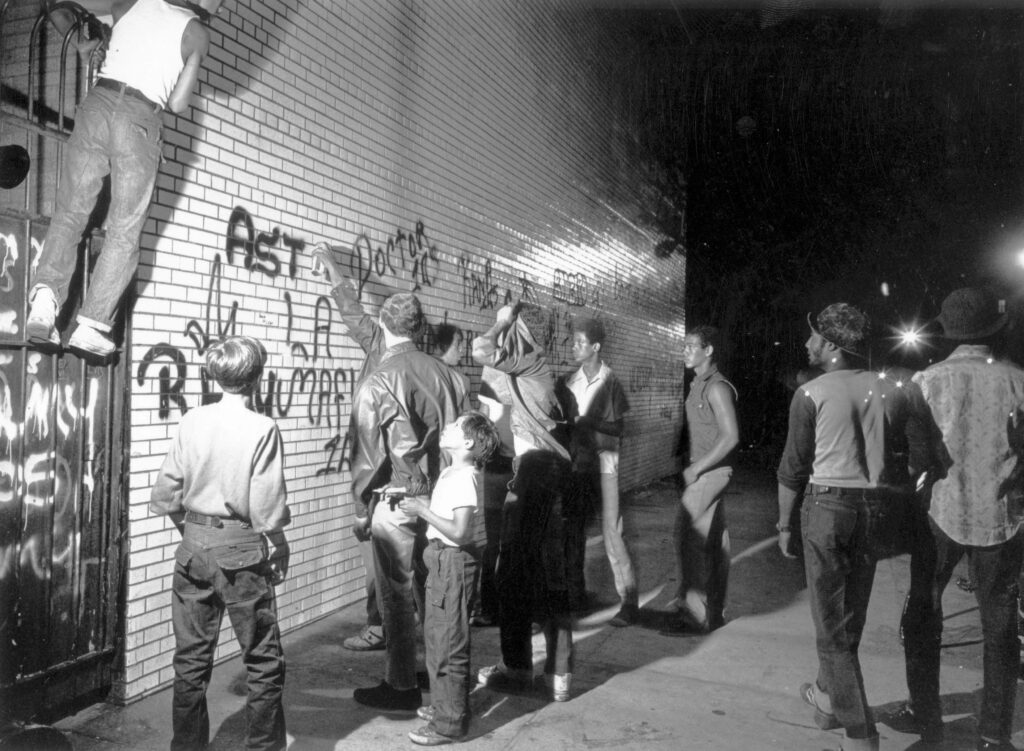 July 1972: A group of youths spraypaint graffiti on a New York wall.