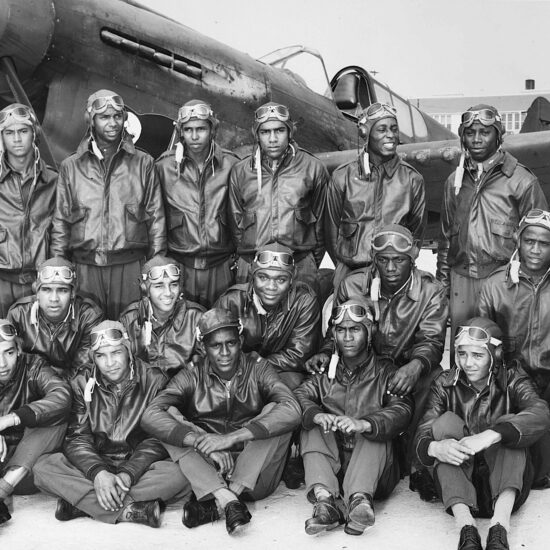 Photograph of Class SE 43 K newly commissioned pilots (Tuskegee Airmen) at Tuskegee Army Flying School, in bomber jackets with a fighter airplane, Tuskegee, Alabama, 1942.
