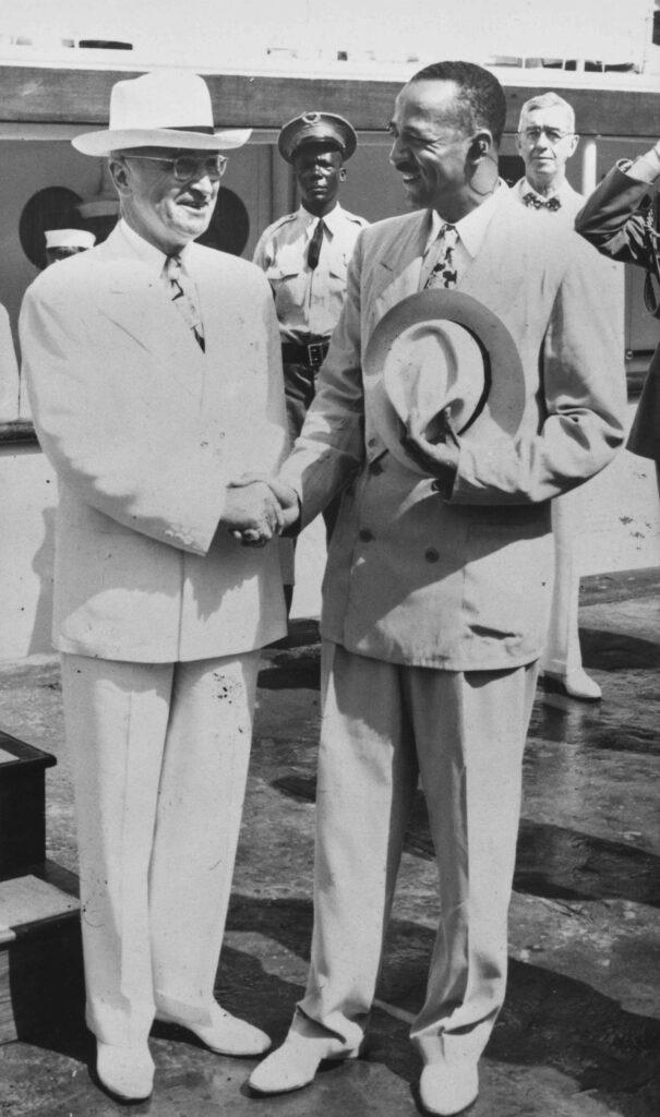 American politician Harry S Truman, President of the United States, shakes hands with American judge, public official, lawyer and civil rights advocate William H Hastie, Governor of the United States Virgin Islands, holding his hat to his chest, at Drake's Seat, on Saint Thomas in the Virgin Islands, 22nd February 1948. Truman visited St. Thomas during a vacation cruise of the area. Hastie was the first African American to serve as a federal judge, a federal appellate judge, and Governor of the United States Virgin Islands.