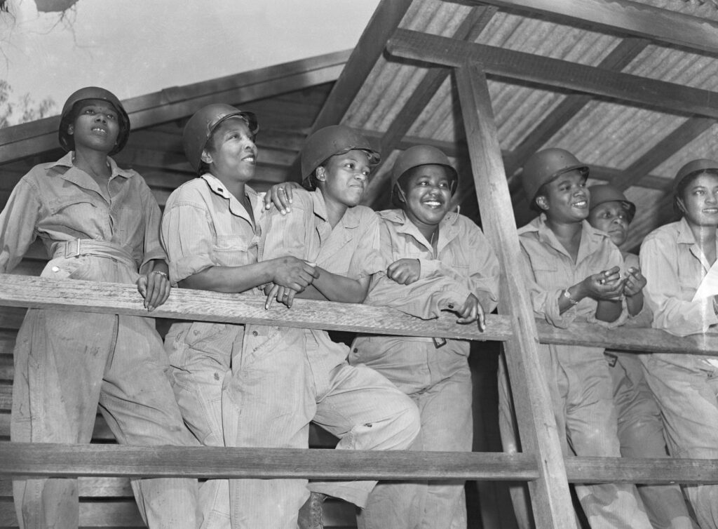 Leaning on a porch rail, waiting for their turn at morning exercises are (l-r): 2nd Lts. Joan L. Hamilton, Marjorie S. Mayers, Prudence L. Burnes, and Inez E. Holmes. All are military nurses training to be sent to advanced posts on the Southwest Pacific.