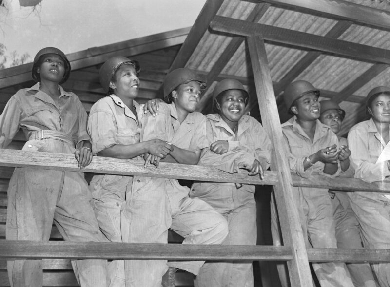 Leaning on a porch rail, waiting for their turn at morning exercises are (l-r): 2nd Lts. Joan L. Hamilton, Marjorie S. Mayers, Prudence L. Burnes, and Inez E. Holmes. All are military nurses training to be sent to advanced posts on the Southwest Pacific.