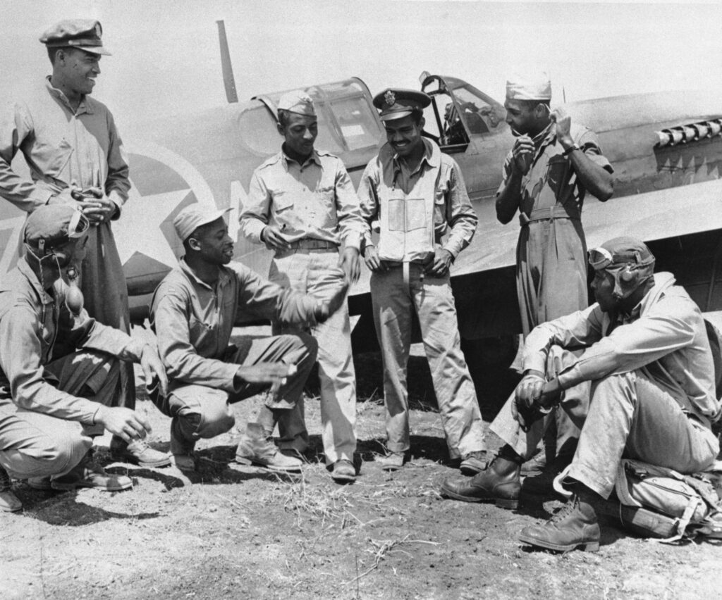 Pilots from the all-black fighter squadron share stories after a raid. The pilots are (from left to right): Lt. Herbert Clark, Lt. Robert Roberts, Lt. Willie Fuller, Lt. William Campbell, Lt. Herbert Carter, and Lt. Erwin B. Lawrence. All the pilots attended Tuskegee University.