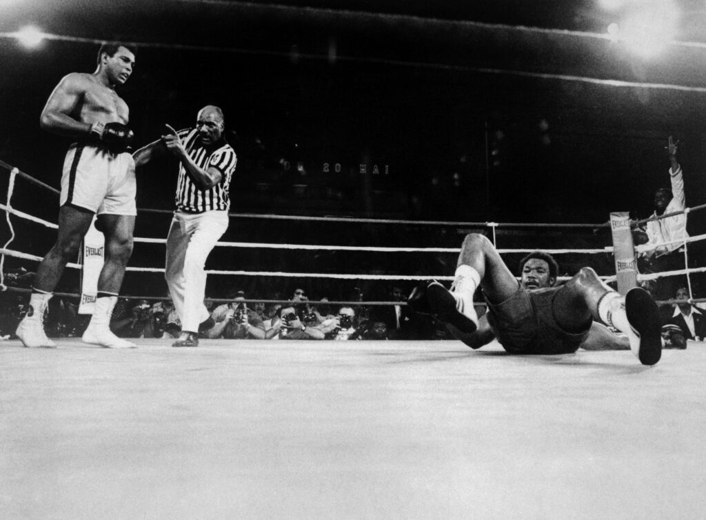 Muhammad Ali (far left) knocks George Foreman (far right) onto his back during the eighth round of their world heavyweight title boxing match in 1974.