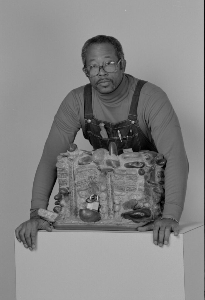 Eldridge Cleaver, a famous Black Panther radical activist in the 1960s, poses with one of his cement and stone sculptures. Cleaver learned masonry skills during the years he spent in prison. 