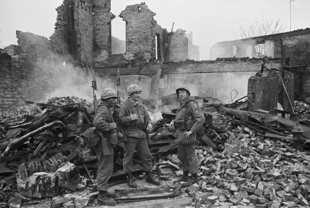 Three soldiers stand amid the rubble of a burned building in Washington, D.C. Riots and looting occurred in many U.S. cities after the assassination of Dr. Martin Luther King, Jr.