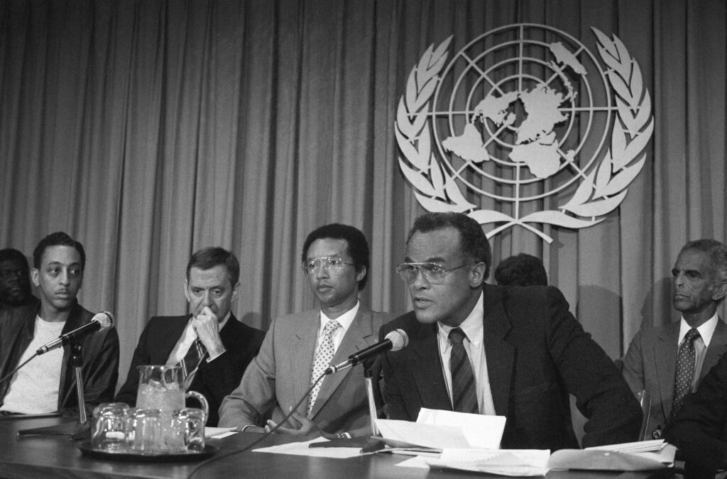 Singer and actor Harry Belafonte speaks at a news conference at the United Nations Headquarters to announce the formation of Artists and Athletes Against Apartheid. At left are actors Gregory Hines and Tony Randall and tennis notable Arthur Ashe.